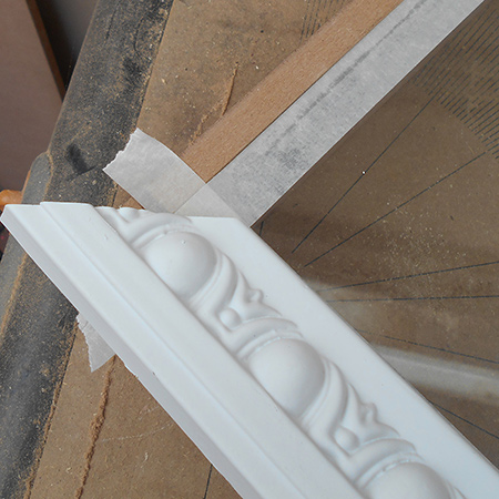 5. Cut one end of the pine moulding or polystyrene cornice and place at the corner of the tape.