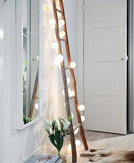 a ladder made using cut branches becomes a decorative feature - inexpensive and dramatic - with string fairy lights and ping pong balls