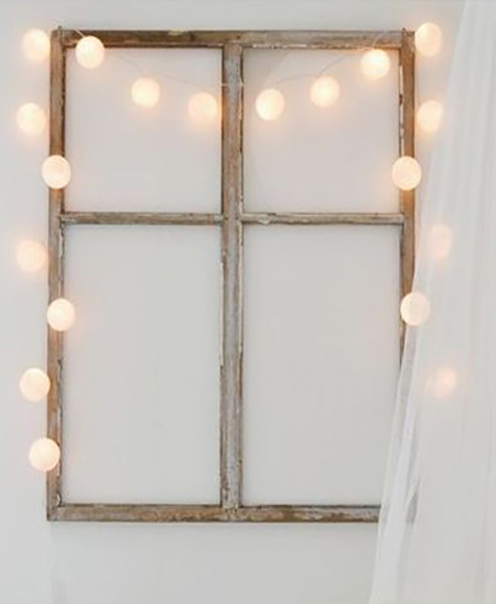 an old window frame is wrapped with a string of fairly lights