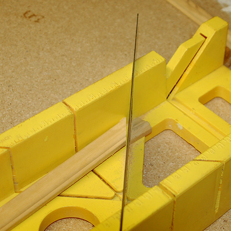 Use a mitre saw or mitre box to cut the moulding that fits on top of the frame around the centre opening.  