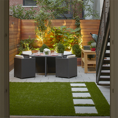 This once bare courtyard and tiny garden are transformed into a stunning outside dining area that also provides plenty of space for entertaining. Artificial turf provides a lovely bed of green in this shady area.