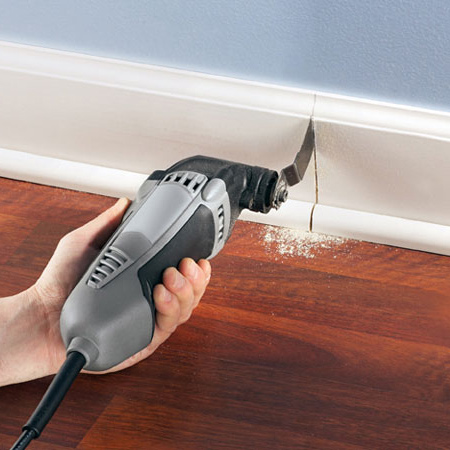 Use a flush-cutting wood blade attachment. Hold the blade flat against the flooring and plunge-cut.