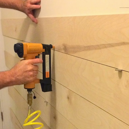 Use a pneumatic brad nailer to attach planks or board to a backing board or drywall.