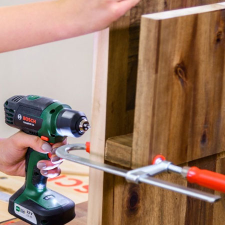 5. Attach the magazine section to the vertical panel with wood glue and 50mm screws. Use clamps to hold the piece in place to make it easier to drill pilot holes.