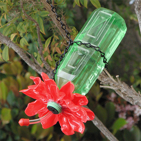 Feed humming birds with this plastic bottle upcycled into a nectar feeder. The flower around the bottle head is made using melted plastic spoons... amazing! 