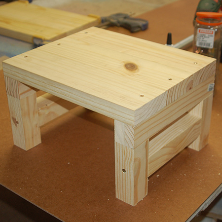 7. Turn the stool over to drive 60mm screws through the top into the leg assembly on both sides. 