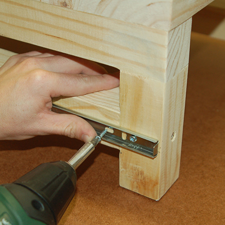 11. Place the small step stool underneath the large step stool and pull out the runners to be able to secure to the leg rail of the small stool. Drive in two screws at the front end of the runner. 
