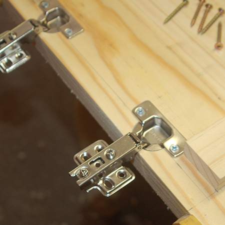 14. Secure the concealed hinges onto the top using 16mm screws.