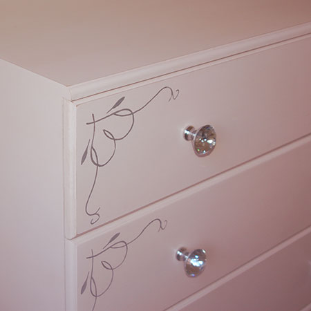 Crystal knobs and hand painted stencil design on drawer fronts.