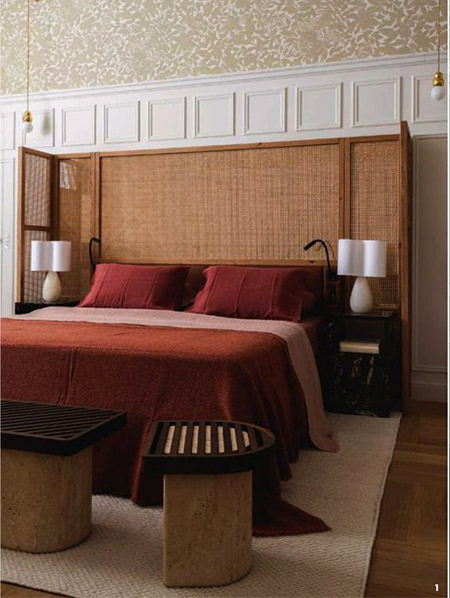 A broad screen, covered in a smart grass cloth creates an inviting enclosure around the bed, complete with modern lamps, and bedside cabinets in walnut. 
