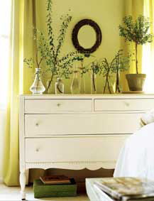 A white distressed drawer unit is crowned with greenery