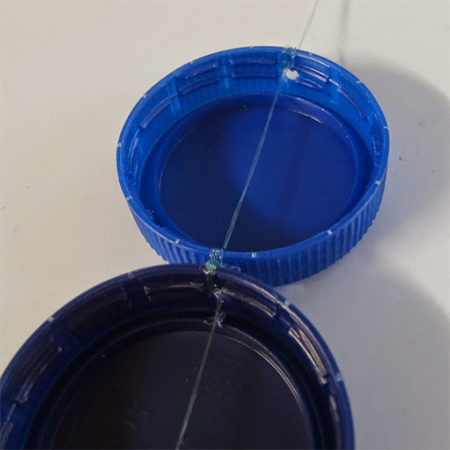 thread nylon line through recycled plastic bottle caps tops to make curtain