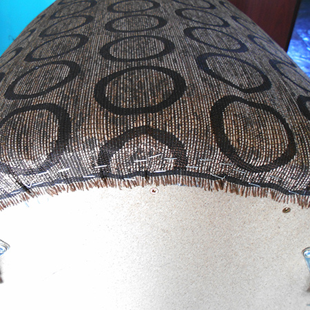At this stage we can staple the outer fabric to the base of the frame, making sure that the inside frame pleats are on top of the frame all the way around. Start at the back of the chair and pull taut before stapling to the base. I applied a double row of staples all the way around.&nbsp;