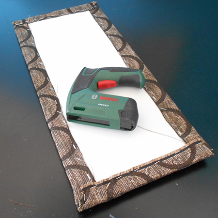 A piece of fabric was wrapped over and stapled at the back. Make sure the corners are not too bulky or you will find that the panel will not sit flat on the front of the chair.