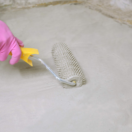 Use a plastering trowel, notched/toothed squeegee, or specialist spiked roller, to smooth an area before continuing to apply more compound 