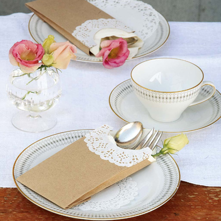 Make a delicate cutlery holder using plain, brown paper packets and a paper doily. The doily adds a lace-like trim that turns something inexpensive into an attractive finishing touch for a special table setting.