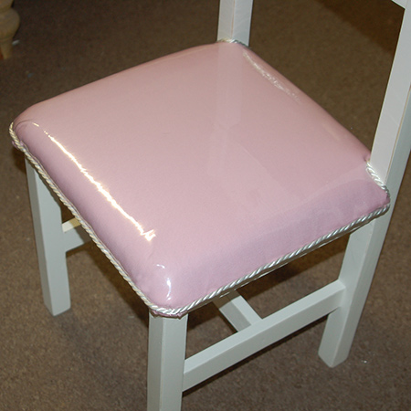 The silky rope is glued around the edge of the seat using a hot glue gun and nicely covers up the staples on the upholstered kiddies seat