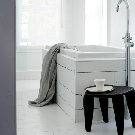 A modern bathtub is clad in reclaimed wood planks painted white