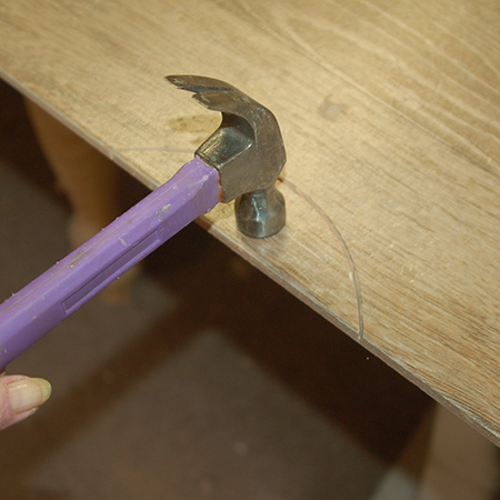 You know when you have cut deep enough when you can simply tap the cut section with a hammer and it falls away. If it doesn't, run the cutting disk along the groove again until it is easy to tap away the piece to be removed. Place the tile over the edge of the board and lightly tap with a hammer.