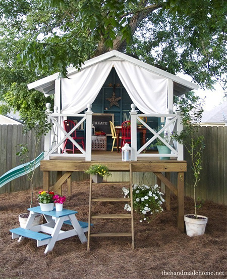 A more permanent design, this treehouse-style playroom offers the ultimate fun room for kids. It even has a slide on one side to add to the fun. Mounted on a timber platform, the playroom is a timber frame topped off with an IBR roof. Drapes of outdoor fabric offer privacy and shade during the summer months.
