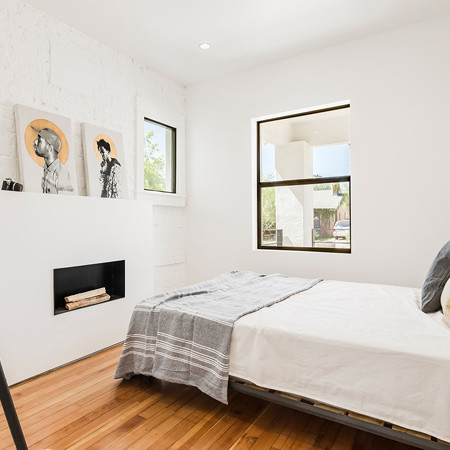 In the main bedroom a exposed brick and mortar wall blends with the natural wood floor 