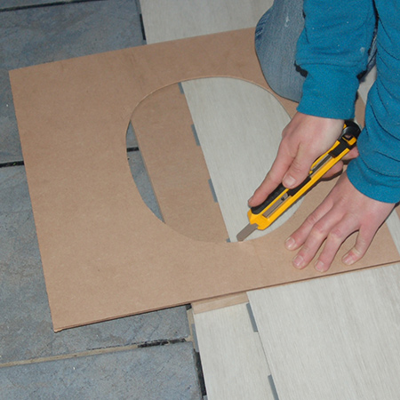 After cutting out the shape on the cardboard profile, this is transferred onto the LVT planks that need to be cut to fit around the shape. One great advantage of fitting LVT is that it is easy to cut with a Stanley or utility knife. 
