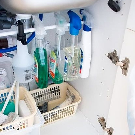 Contain clutter under a kitchen sink by adding a tension rod to hang cleaning products.