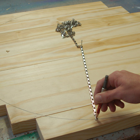 2. Hammer a nail into the centre of the glued boards and use a length of chair and pencil to draw a 600mm diameter circle.