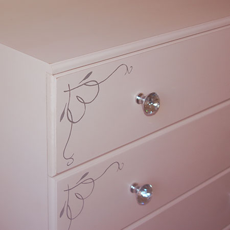 Crystal knobs and hand painted stencil design on drawer fronts.