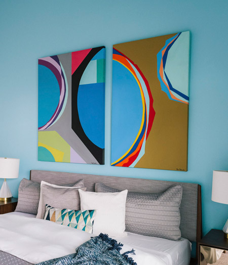 IIn a room decorated in neutral shades, like the bedroom above and below, a splash of colour can make all the difference. These paired arworks definitely stand out on the blue wall.
