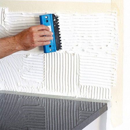 apply tile adhesive to wall
